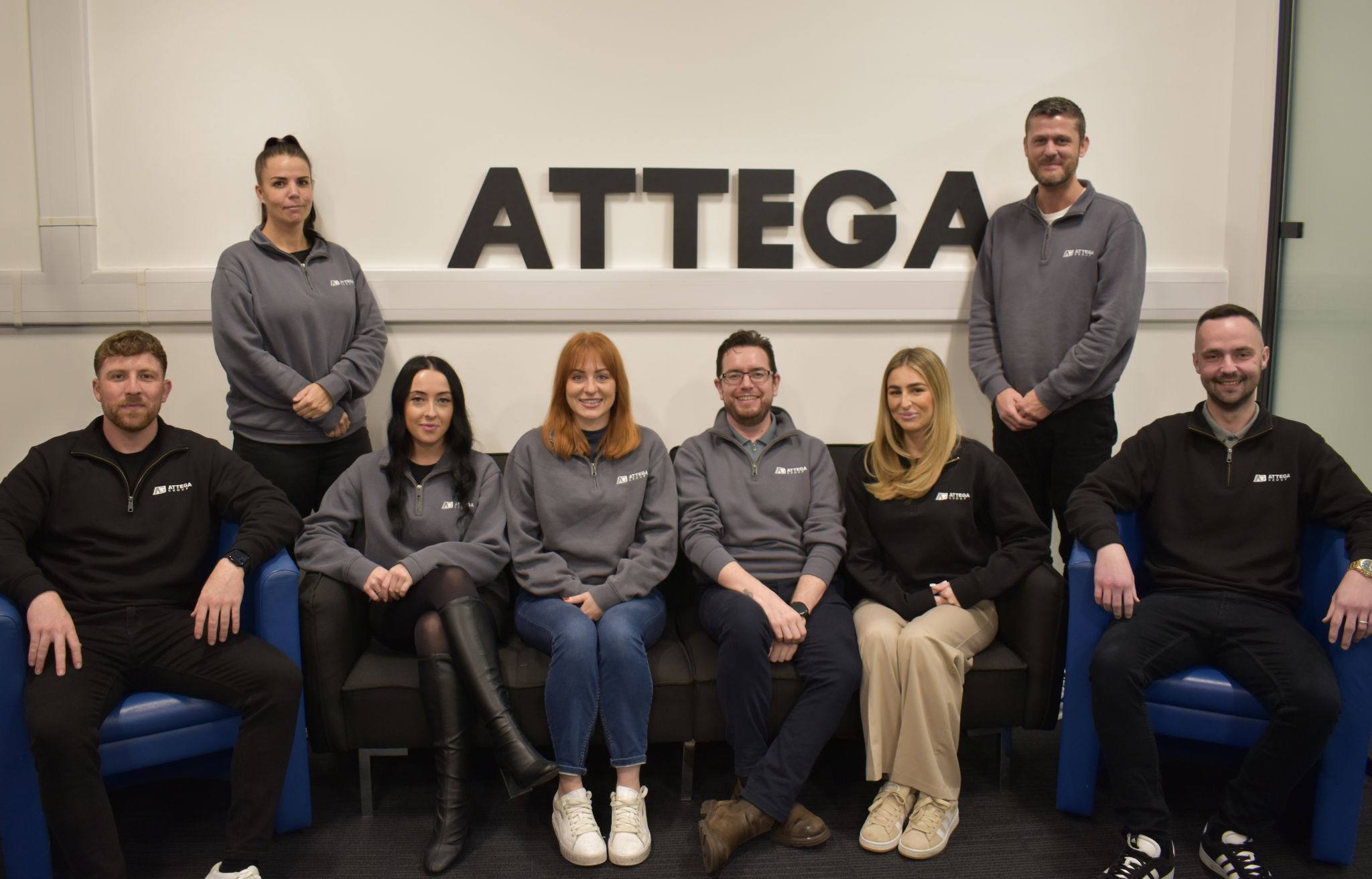 a Group image of the Attega team with the Attega sign behind them
